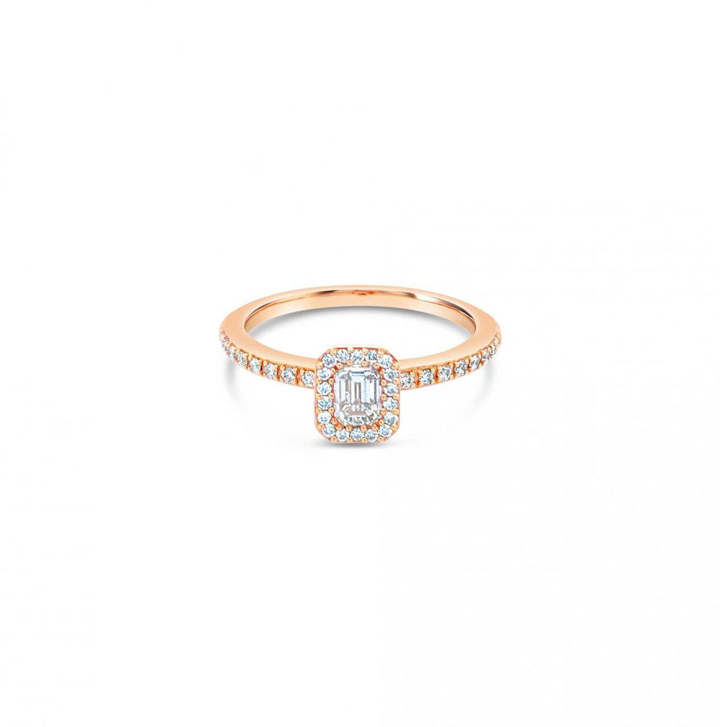 An 18ct rose gold diamond halo ring with an emerald cut central diamond and a halo of round diamonds around it.