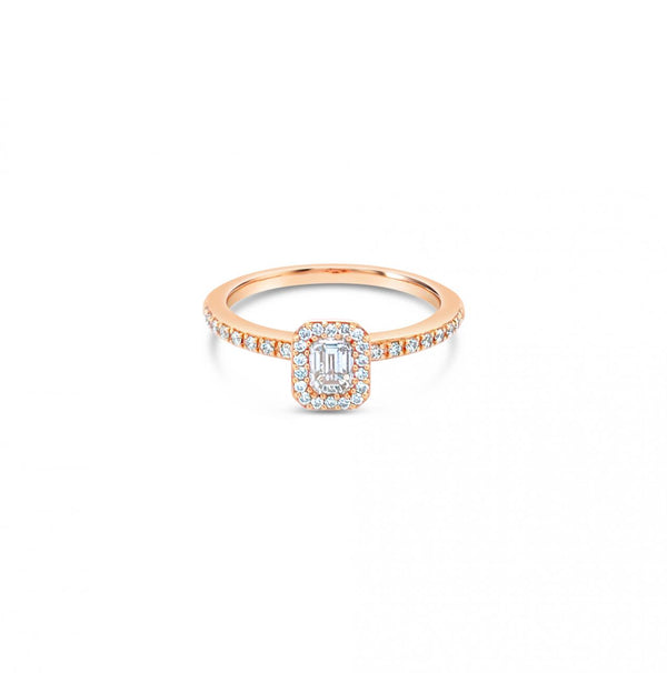 An 18ct rose gold diamond halo ring with an emerald cut central diamond and a halo of round diamonds around it.