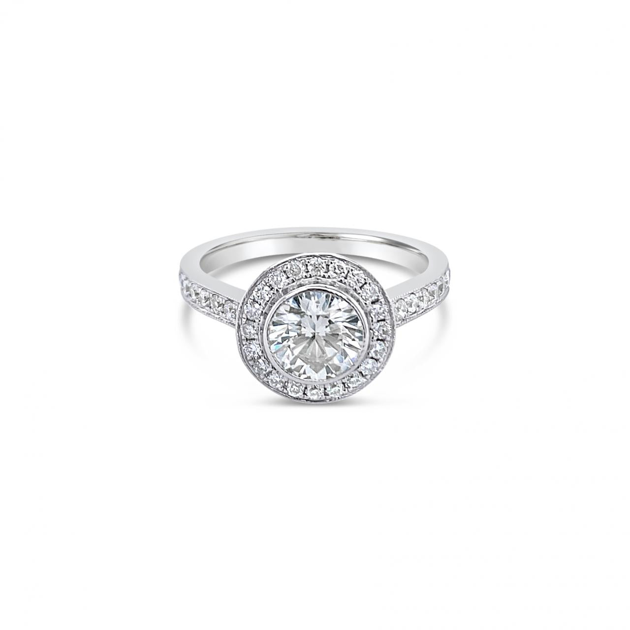 18ct white gold diamond halo ring featuring a 1.00ct round brilliant cut centre diamond with bead-set halo, undercarriage, and shoulders with millgrain finish.