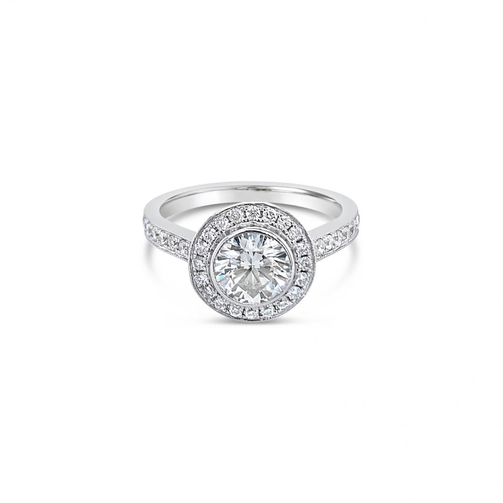 18ct white gold diamond halo ring featuring a 1.00ct round brilliant cut centre diamond with bead-set halo, undercarriage, and shoulders with millgrain finish.