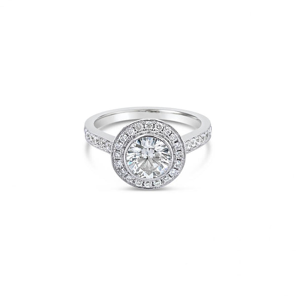 18ct white gold diamond halo ring featuring a 1.00ct round brilliant cut centre diamond with bead-set halo, undercarriage, and shoulders with millgrain finish.