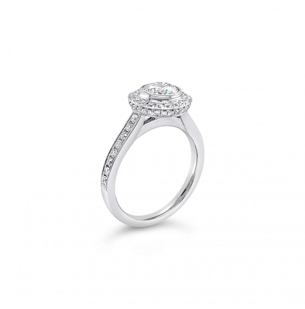18ct white gold diamond halo ring featuring a 1.00ct round brilliant cut centre diamond with bead-set halo, undercarriage, and shoulders with millgrain finish.