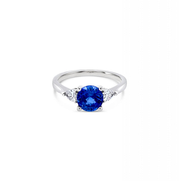 18ct white gold ring featuring a 1.32ct round-cut sapphire with pear-cut diamond accents totalling 0.25ct in elegant claw settings.