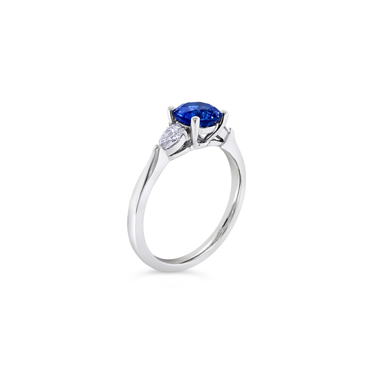 18ct white gold ring featuring a 1.32ct round-cut sapphire with pear-cut diamond accents totalling 0.25ct in elegant claw settings.