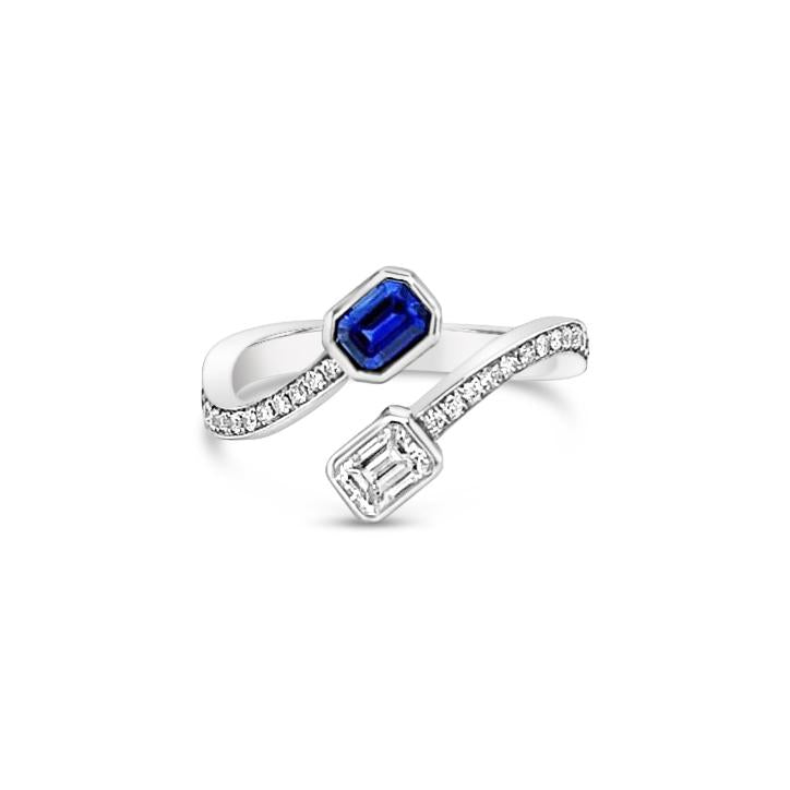 18ct white gold sapphire and diamond crossover ring featuring bezel-set emerald cut stones with curved bead-set shoulders.