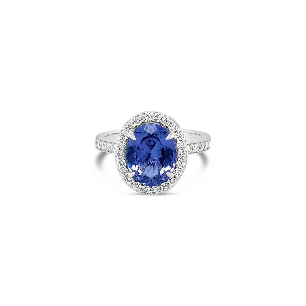 18ct white gold ring featuring a 2.30ct oval cut tanzanite surrounded by a halo of 34 round brilliant cut diamonds with diamond-set shoulders.